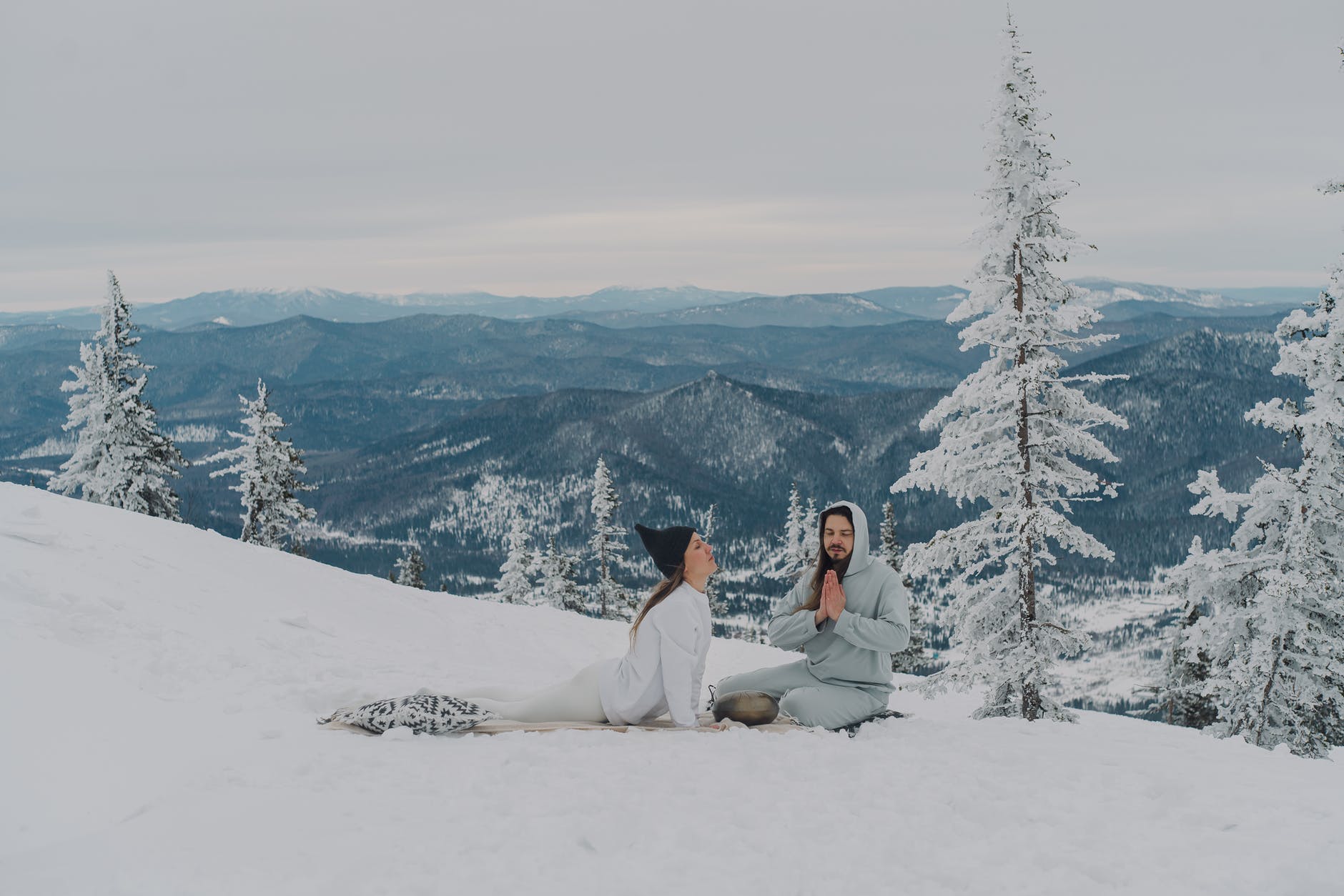 peaceful couple meditating on snowy ground in highland